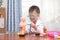 Cute little Asian school boy in doctor uniform playing doctor at home, kid wearing stethoscope learning and play with anatomical
