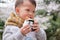 Cute little Asian toddler boy biting & eating Onigiri, Japanese food, Japanese rice ball, rice triangle with seaweed in blossom