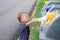 Cute little Asian toddler boy child throwing plastic bottle in recycling trash bin at public park