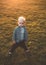 Cute little baby in autumn park with yellow leaves. The boy sits in the autumn leaves in the park. Little boy. Golden