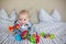 Cute little baby boy, playing at home in bed with lots of colorful toys