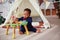 Cute little baby boy playing with wooden developing toy on the carpet at home