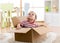 Cute little baby boy sitting inside cardboard box, moving out concept