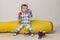 Cute Little Baby Boy Sitting On a Yellow Bean Bag Chair and Playing Toys.