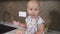 A cute little baby eating a piece of bread. Small cute infant eating bread and sitting in the kitchen. Slowmotion shot