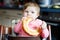 Cute little baby girl eating bread. Adorable child eating for the first time piece of pretzel or croissant. Healthy