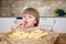 Cute little baby girl enjoying french fries on kitchen