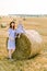 Cute little baby girl sitting on hay stack bale and posing to camera together with her charming young mother. Mommy and