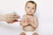 Cute little baby girl waits for the brushing teeth with red toothbrush.  on white background. Mother holds