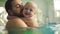 Cute little baby and his father having swimming lesson in the pool. The father is holding his son in his hands and