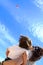 Cute little baby and his mum staring a kite flying high in the sky of a beach at Costa Brava, Girona, Catalonia, Spain