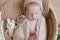 Cute little baby in a knitted hat  lies in a wicker basket decorated with greens