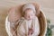 Cute little baby in a knitted hat with a toy bunny lies in a wicker basket decorated with greens