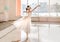 Cute little ballerina in white ballet costume and pointe shoes is dancing in the room