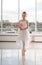 Cute little ballerina in white ballet costume and pointe shoes with is dancing in the room