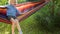 Cute little blond caucasian boy having fun with multicolored hammock in backyard or outdoor playground. Summer active leisure for