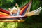 Cute little blond caucasian boy having fun with multicolored hammock in backyard or outdoor playground. Summer active leisure for