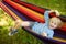 Cute little blond caucasian boy relaxing and having fun in multicolored hammock in backyard or outdoor playground. Summer active