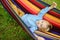 Cute little blond caucasian boy relaxing and having fun in multicolored hammock in backyard or outdoor playground. Summer active