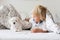 Cute little blond child, toddler boy, reading book with white puppy maltese dog