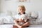 Cute little blond child, toddler boy, reading book with white puppy maltese dog