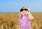Cute little blond girl playing in a wheat field