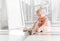 Cute little blonde girl sitting on the floor and tying ballet shoes