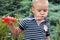 Cute little boy with blond hair and blue eyes blows bubbles from plastic toy with serious look.