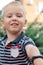 Cute little boy with blond hair and blue eyes reaches out the hand with electronic watch towards the camera, smiling.