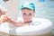 A cute little boy in a blue baseball hat swimming in the sea in an inflatable ring