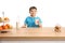 Cute little boy in a blue t-shirt holding a glass of milk behind a wooden counter