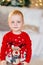 cute little boy with a bruise under his eye in a red Christmas sweater.