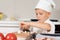 Cute little boy in a chefs toque slicing mushrooms