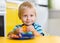 Cute little boy eats his lunch sitting at a table