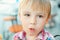 Cute little boy eats tasty belgian waffle on summer terrace.