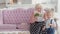 Cute little boy giving bouquet of pink tulips to smiling senior woman sitting on couch. Blond Caucasian toddler