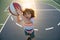 Cute little boy holding a basket ball trying make a score.