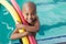 Cute little boy holding foam rollers by the pool