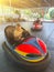 Cute little boy with mother and sister having fun in electric bumper car in amusement park