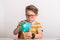 Cute little boy with piggy bank. Portrait of a little boy take money from moneybox. Little kid holding a piggy bank. Boy