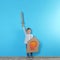 Cute little boy playing with cardboard sword and shield near color wall
