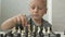 Cute little boy playing chess at home.