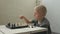 Cute little boy playing chess at home.