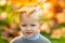 Cute little boy playing with leaves in autumn park, autumnal mood. Yellow maple leaves on kids head.