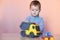 A cute little boy playing with model car collection. Toy mess in child room.