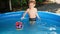 Cute little boy playing with toy ship or boat in outdoor inflatable swimming pool at house backyard garden. Concept of