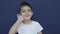 Cute little boy shows thumbs up gesture, happy facial expression emotion, slow motion isolated on blue background