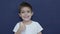 Cute little boy shows thumbs up gesture, happy facial expression emotion, slow motion isolated on blue background