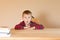 Cute little boy sits at a desk. He is surprised and widens his eyes. Back to school concept