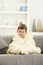 Cute little boy sitting in bathrobe at home sofa